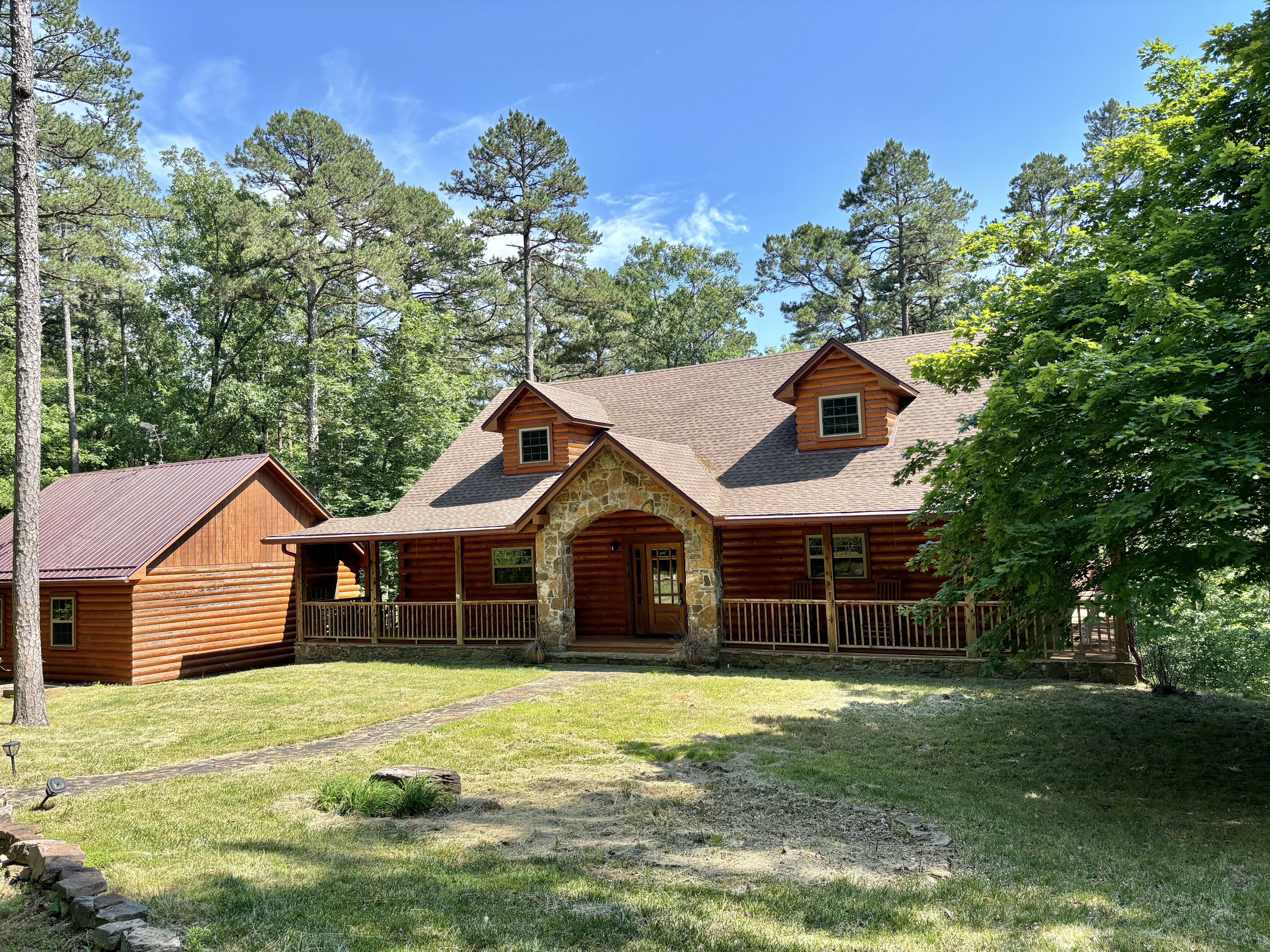 Wooden cabin with garage in forested mountain area.