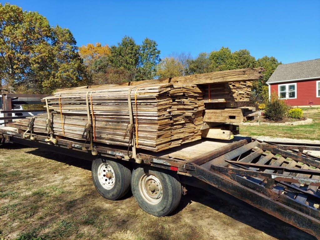 Flatbed trailer loaded with stacked wooden planks.