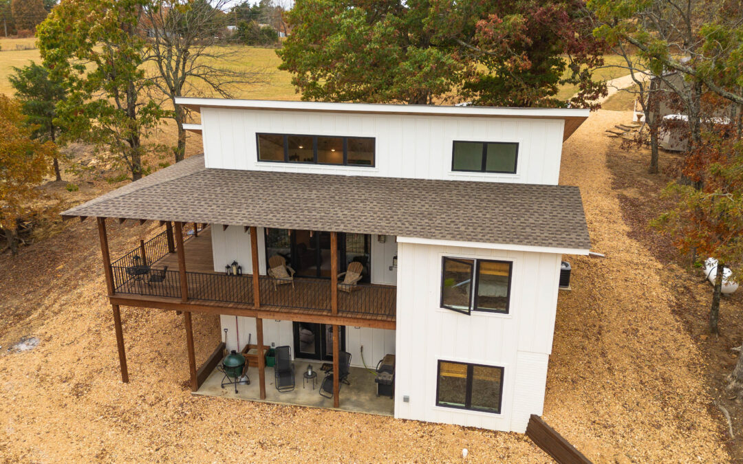 Modern white house with wooden porch in fall setting.