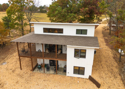 Modern white house with wooden porch in fall setting.