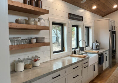 Rustic kitchen with open shelving and farmhouse sink.