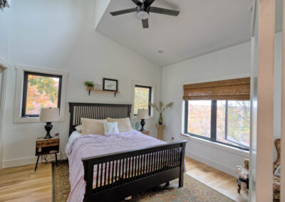 Cozy bedroom with large windows and wooden floor.