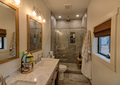 Modern bathroom with double sinks and glass shower.