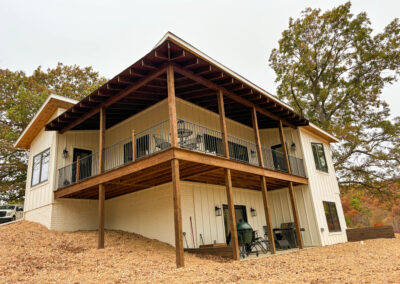 Modern two-story house with covered patio and woodland view.